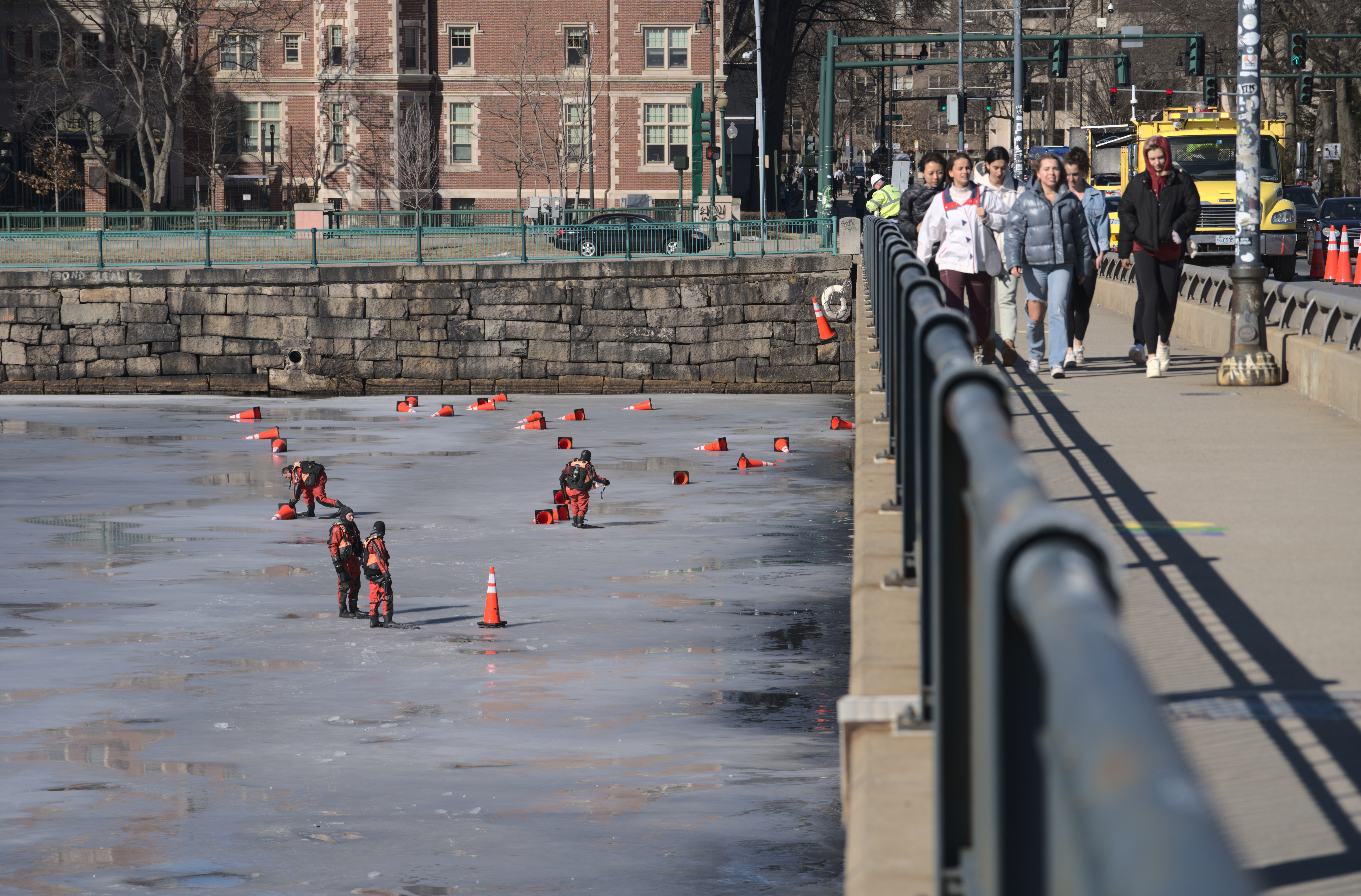 Workers in SCUBA gear retrieve cones from the frozen Charles River in January 2022.